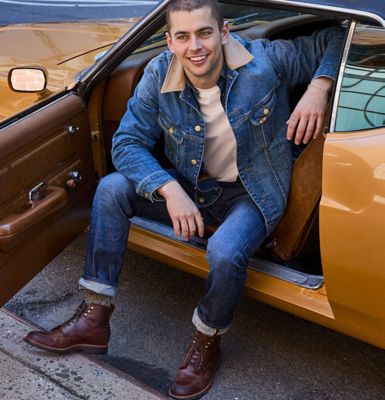 Guy sitting in Orange classic car wearing Lee Gold Label.
