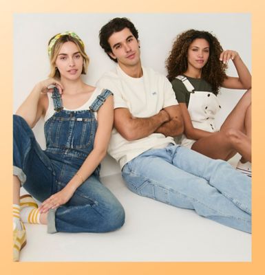Friends standing against a wall wearing Lee workwear.