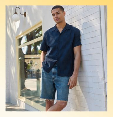Man sitting on a city sidewalk wearing Lee shorts.