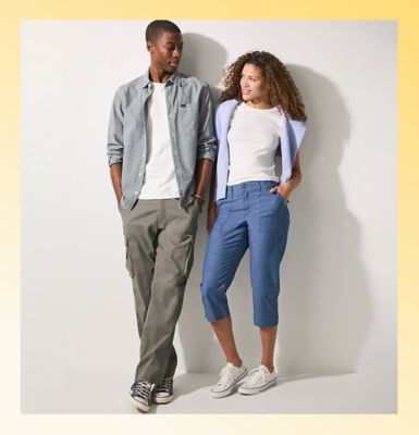 Friends wearing Lee pants and capris standing against a wall.