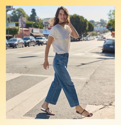 Woman standing against a wall wearing Lee womens wide leg jeans.